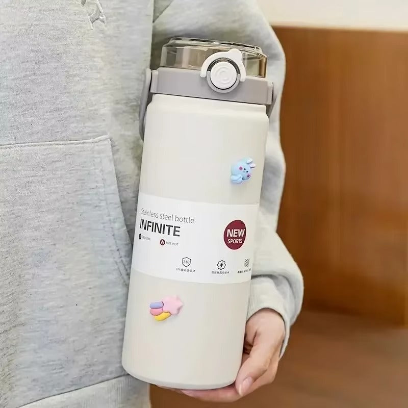 Bouteille isotherme blanche DiYiB INFINITE en acier inoxydable avec anse grise, tenue à la main