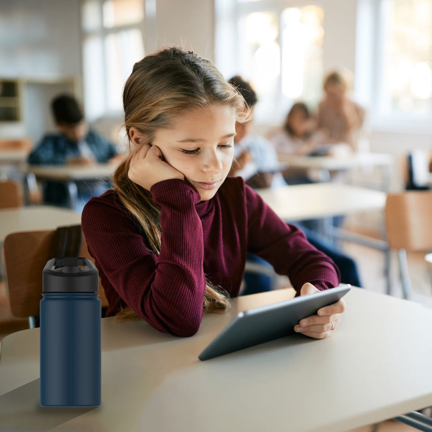 Gourde isotherme bleue posée sur un bureau d’école à côté d’une élève