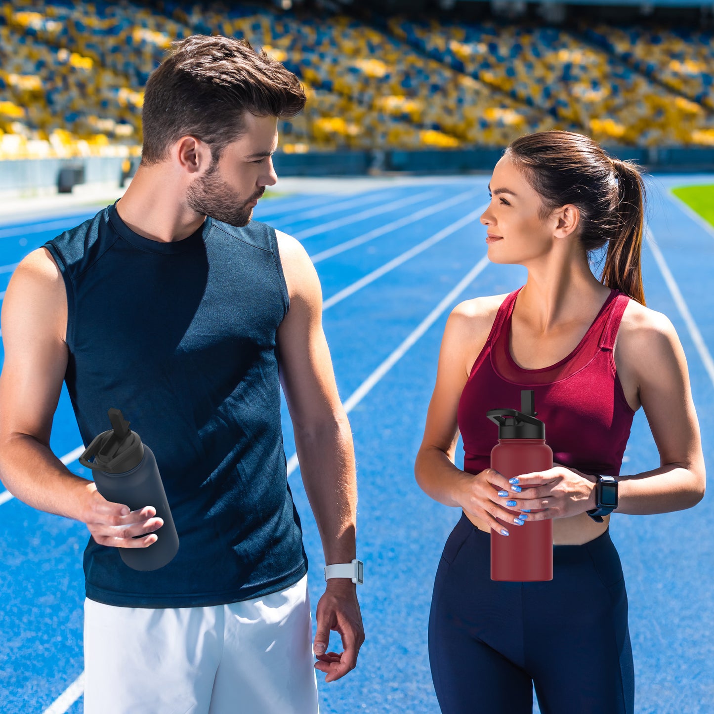 Homme et femme sportifs tenant des gourdes isothermes WATERSY, noire et rouge, sur une piste d’athlétisme