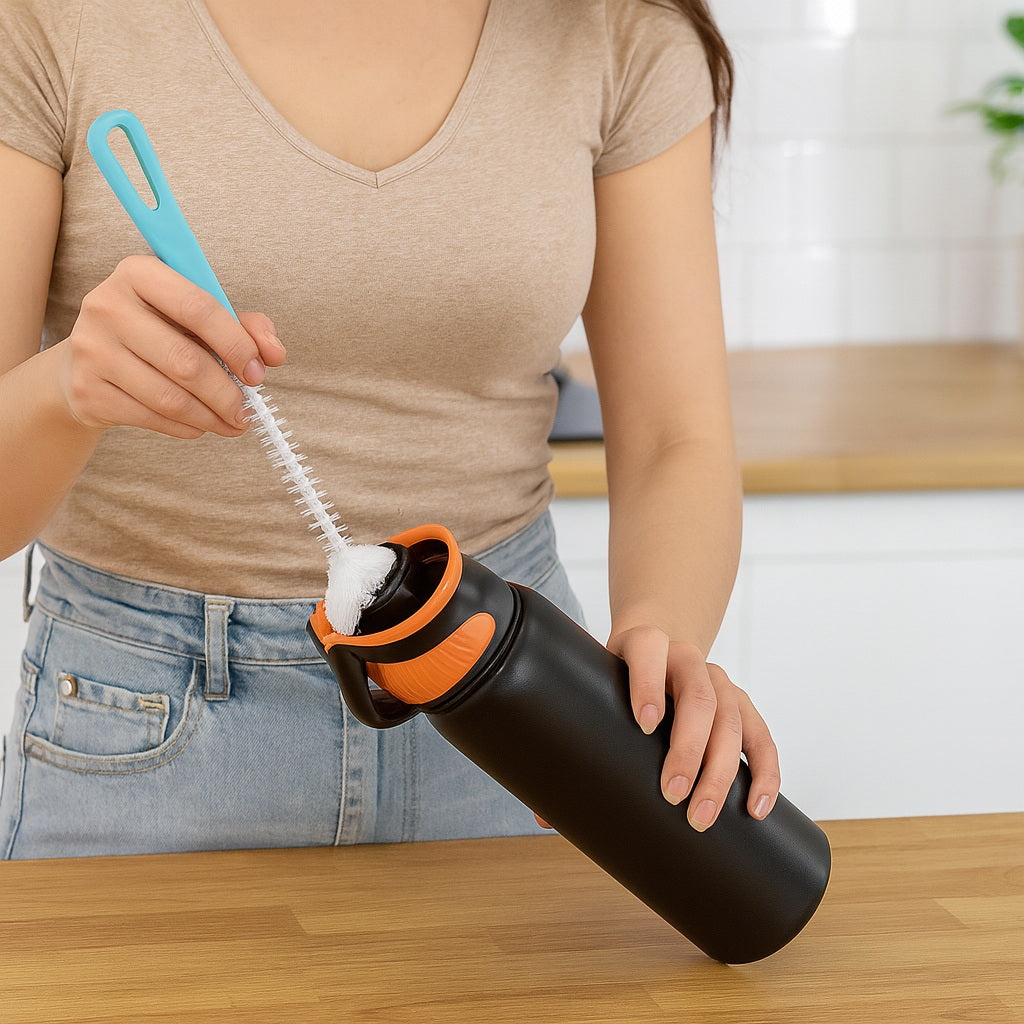 Femme nettoyant une gourde isotherme noire avec bouchon sport orange à l’aide d’une brosse de nettoyage.